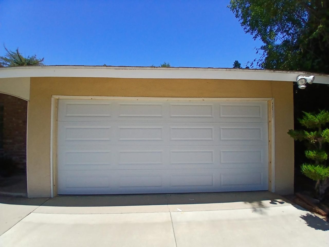 White long-panel steel garage door installed on a stucco home in Clovis, CA