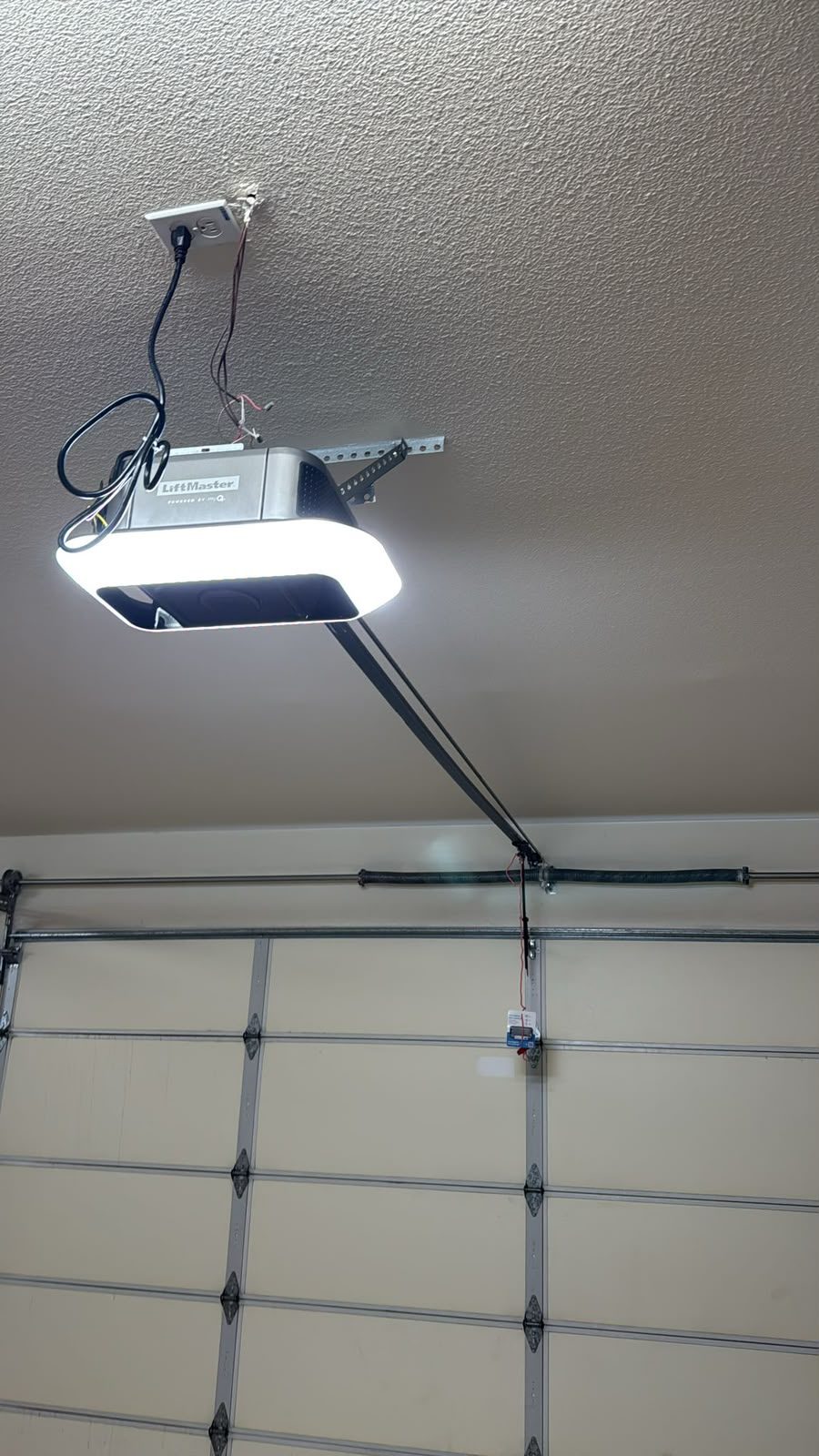 LiftMaster ceiling-mounted garage door opener with rail, safety wiring and LED light installed in a Clovis garage